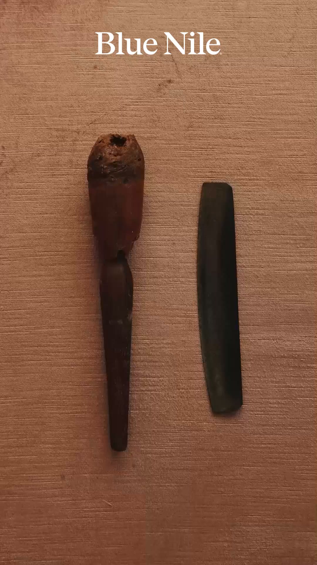 The image displays two ancient artifacts, possibly tools or decorative items, against a textured, light brown background. The artifact on the left is reddish-brown and appears to be made of wood or bone, with a rough, hollowed-out top. The artifact on the right is dark, elongated, and smooth, possibly made of stone or metal. White text at the top of the image reads "Blue Nile." The copy, "A legacy of craftsmanship. A new chapter. Something exclusive is being unveiled at Blue Nile.," is overlaid on the image, creating a sense of mystery and anticipation around the unveiling of something new from the brand.