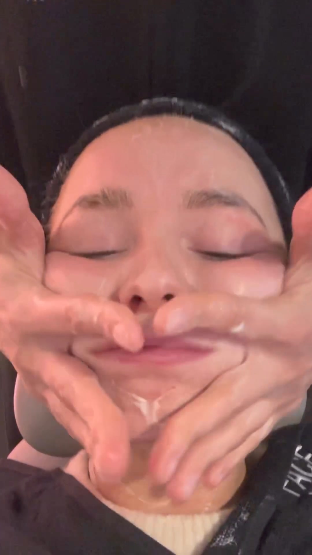 A close-up shot shows a person receiving a facial massage from a spa professional. The person's eyes are closed, and their face is being gently manipulated by the hands of the masseuse. White cream or serum is visible on the person's face and chin, suggesting a skincare treatment is in progress. The text overlay reads 'Try FACEGYM's viral Workout for yourself 😁', directly addressing the viewer and inviting them to experience the service.
