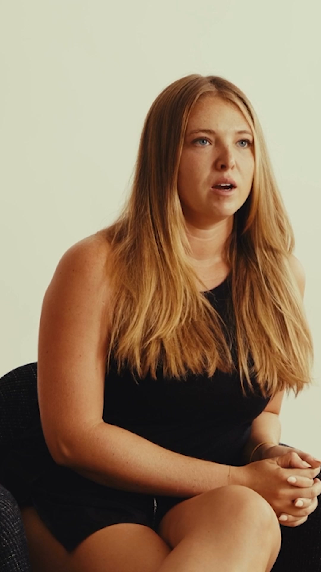 A young woman with long blonde hair and blue eyes is shown from the chest up, looking off to the side with her mouth slightly open. She is wearing a black sleeveless top. The background is a plain, light-colored wall. Text overlaid on the image reads: "Whatever your reason, hydrate for it. Liquid I.V.® Hydration Multiplier: rapid absorption for every mile ahead."
