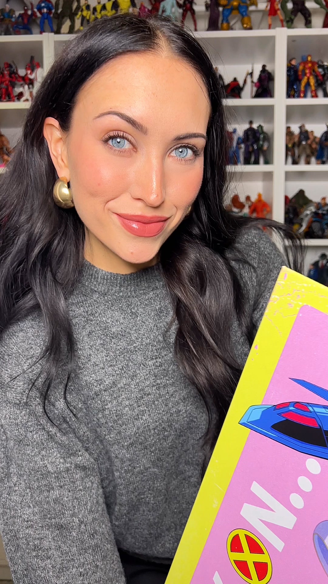 A woman with dark hair and blue eyes smiles at the camera, holding a Displate metal poster. The poster has a pink background with a blue spaceship graphic and white text. Behind her, shelves are filled with collectible action figures. The text on the creative reads "Wall art that gets you!" and "A unique metal poster designed for the 21st century. Premium quality, easy setup." The ad copy also includes a call to action with a link to Displate's website.