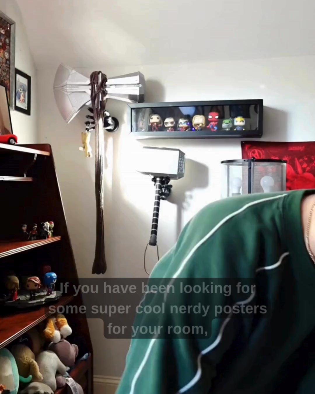 The image shows a room decorated with various nerdy collectibles, including a replica of Thor's axe and hammer, and a shelf of Funko Pop figures. Text is overlaid on the bottom right of the image, asking if the viewer has been looking for cool nerdy posters for their room. The overall impression is that of a fan's personal space, showcasing items related to popular culture and fandom.
