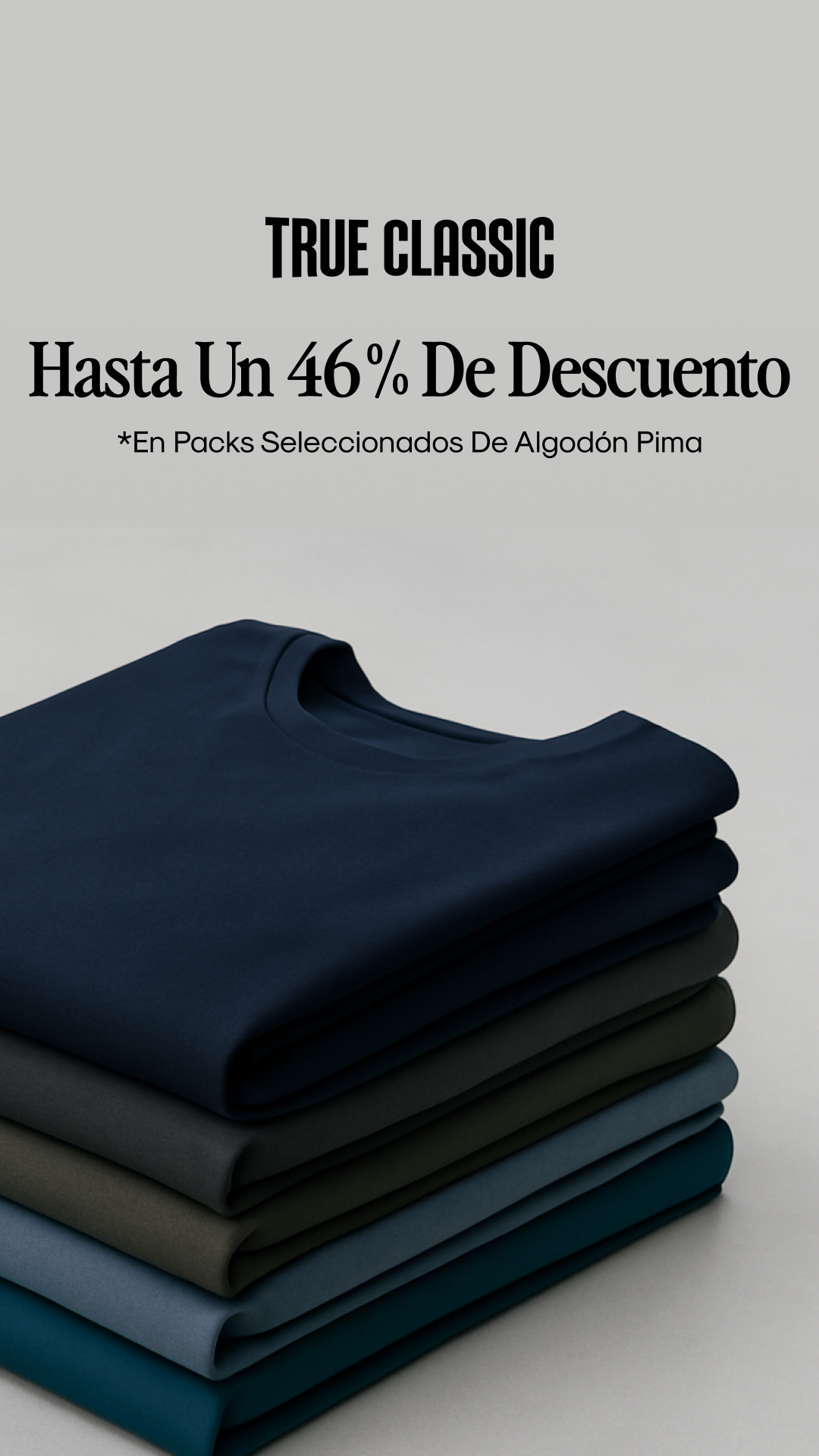 The ad displays a stack of folded t-shirts in various dark colors, from navy blue to teal. Above the t-shirts, large, bold text reads "TRUE CLASSIC" followed by "Hasta Un 46% De Descuento" (Up to 46% Off). Below this, smaller text states "*En Packs Seleccionados De Algodón Pima" (*On Selected Pima Cotton Packs). The visual focuses on the product and the discount offer.
