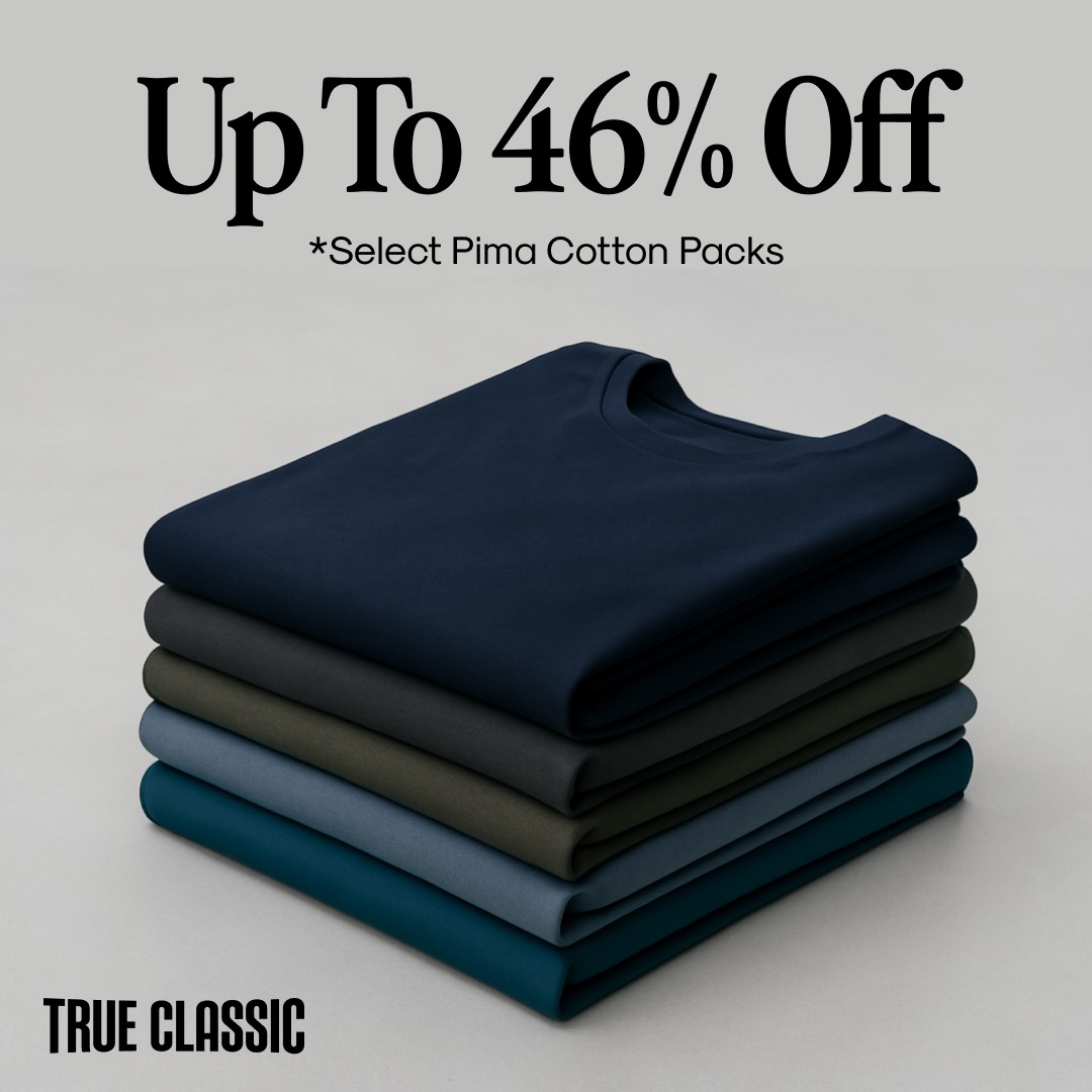 A stack of folded t-shirts in various dark colors is shown against a light gray background. The top t-shirt is navy blue, followed by charcoal gray, olive green, slate blue, and a teal color at the bottom. Large text at the top of the image reads "Up To 46% Off" with smaller text below it stating "*Select Pima Cotton Packs". The "TRUE CLASSIC" logo is visible in the bottom left corner.