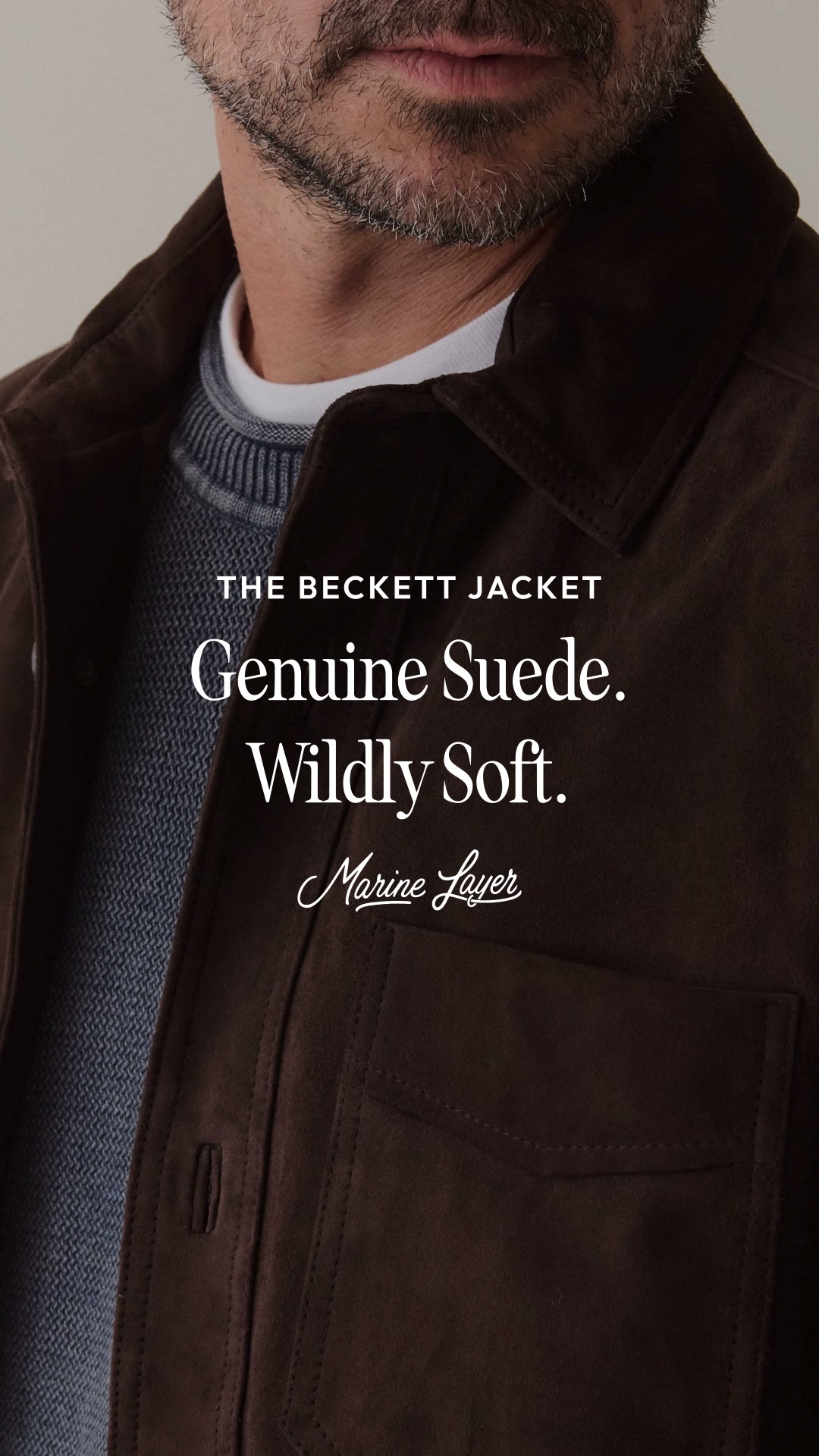 A close-up, chest-up shot of a man wearing a dark brown suede jacket over a grey textured sweater and a white t-shirt. The man has a beard and is looking slightly down and to the side. White text overlays the image, reading "THE BECKETT JACKET", "Genuine Suede.", and "Wildly Soft.". Below this text, the brand name "Marine Layer" is written in a script font. The overall impression is one of sophisticated comfort and quality material.