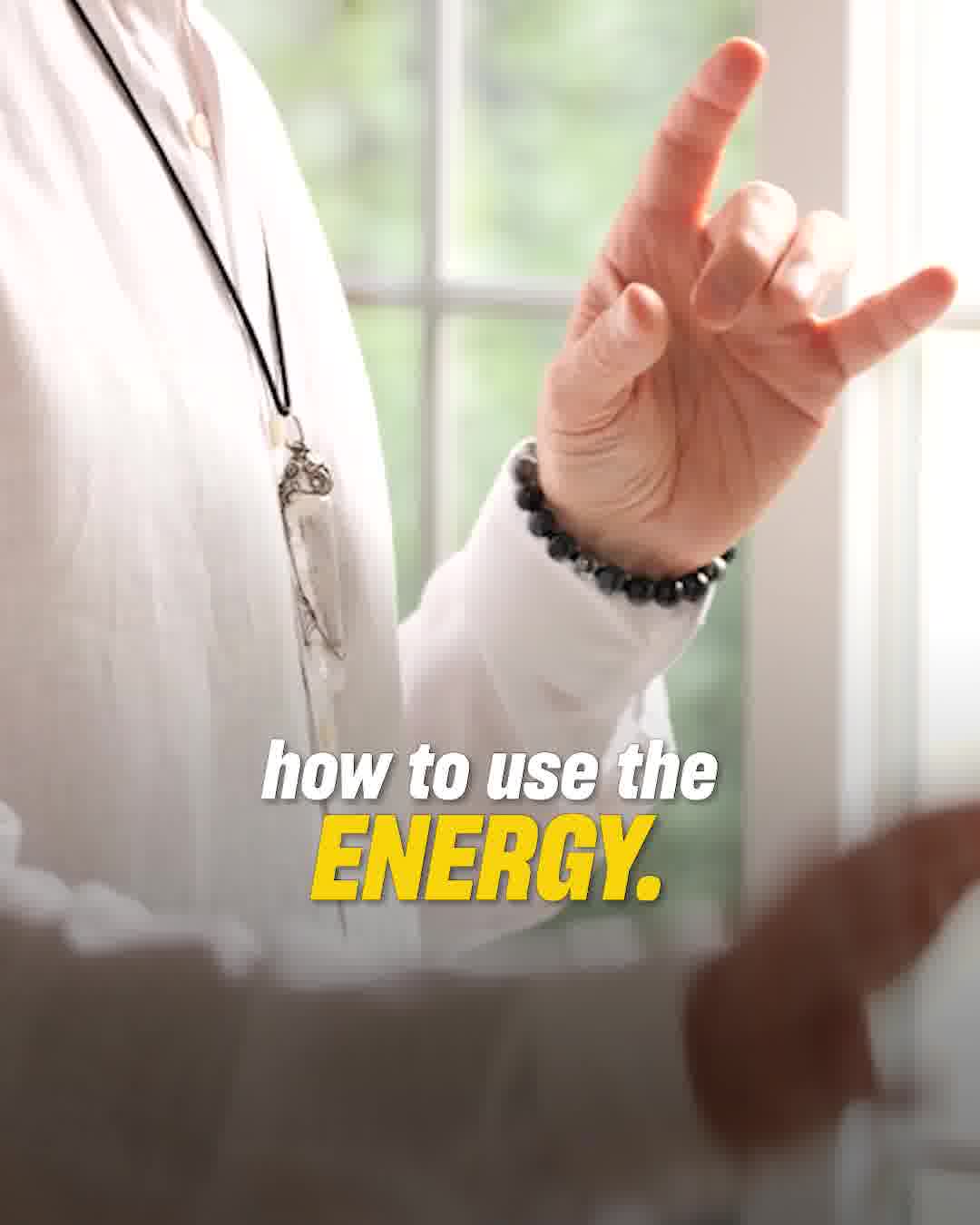 A close-up shot shows a person wearing a white shirt and a necklace, with their hand raised in a gesture. The hand has a beaded bracelet on the wrist and is forming a "rock on" sign. Overlayed text in white and yellow reads "how to use the ENERGY." The background is blurred, showing a window with light filtering through.