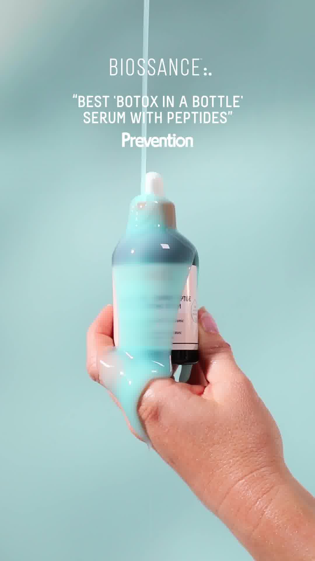 A hand holds a bottle of Biossance serum, with a thick, light blue liquid being dispensed from the dropper and onto the hand. White text overlays the image, with the brand name "BIOSSANCE::" at the top, followed by a quote calling the product the "BEST 'BOTX IN A BOTTLE' SERUM WITH PEPTIDES". Below this, the word "Prevention" is displayed in a larger font.