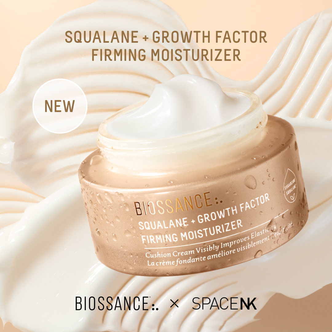 A close-up shot of a Biossance Squalane + Growth Factor Firming Moisturizer jar, with creamy swirls in the background. The jar is golden with water droplets on it, and the lid is slightly ajar, revealing the white cream inside. A circular "NEW" graphic is placed on the top left of the image. The product name and a description of its benefits are visible on the jar. At the bottom, "BIOSSANCE x SPACENK" is displayed.