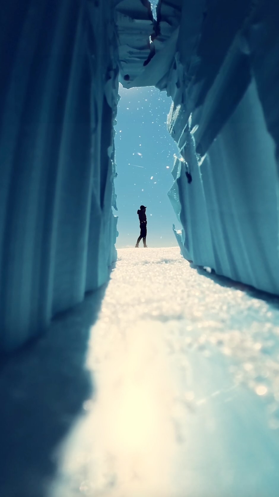 A silhouette of a person stands in a vast, snowy landscape, framed by two large, icy blue structures. The sun shines brightly in the clear blue sky, with small white particles, possibly snow or ice crystals, scattered around. The text overlay reads "Way cheaper than a ticket to Antarctica ❄️" and mentions "Styrofoam, flour, and a camera small enough to make it convincing." It also highlights the "Insta360 GO Ultra" and promotes "Insta360 Labor Day deals" with a call to action to shop and a discount code.