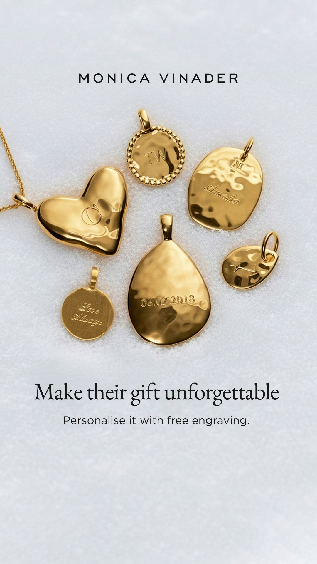A collection of gold pendants from Monica Vinader is displayed on a white, textured surface. The pendants vary in shape and size, with some featuring engraved initials, dates, or phrases like "Love Always." The brand name "MONICA VINADER" is visible at the top. Below the pendants, the headline "Make their gift unforgettable" is overlaid, followed by the sub-headline "Personalise it with free engraving."