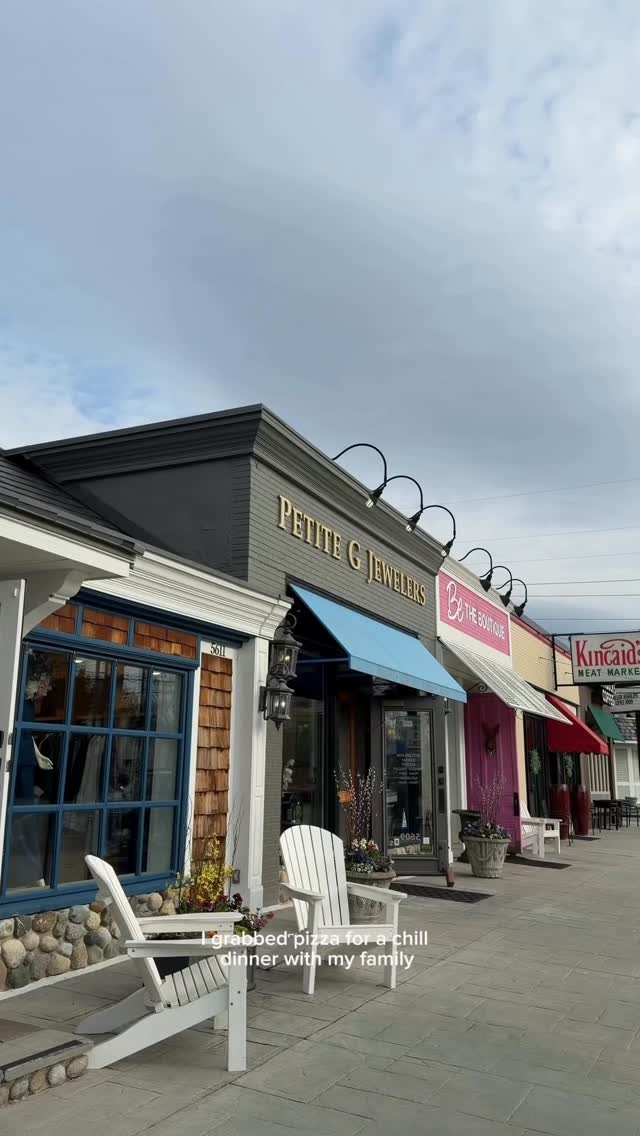 The image shows a row of storefronts on a street, including "PETITE G JEWELERS" and "Be THE BOUTIQUE." In the foreground, two white Adirondack chairs sit on a paved patio area. The text overlay reads, "I love life in the midwest and @cashapp makes it even better! #ad #cashapppartner." The scene evokes a relaxed, pleasant atmosphere.