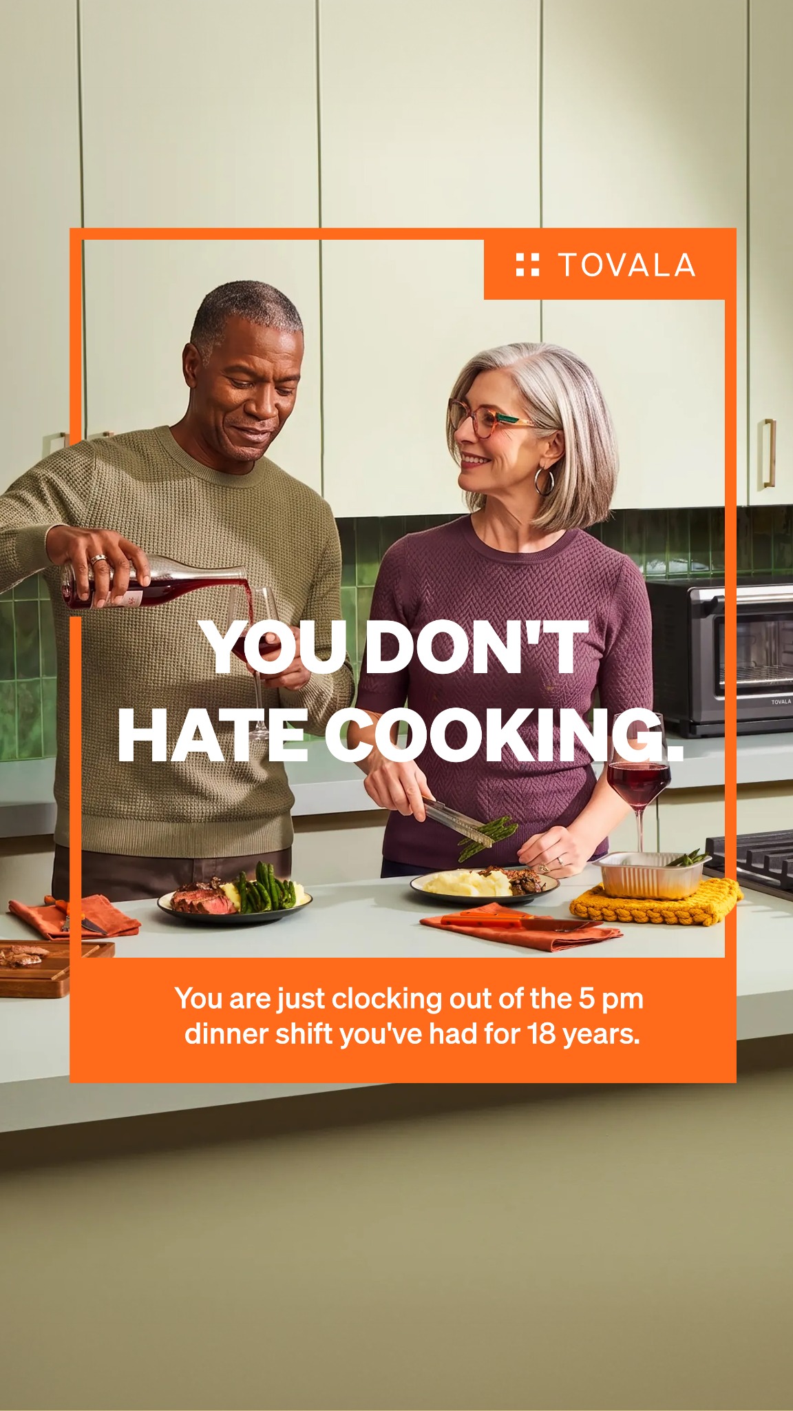 A man pours red wine into a glass while a woman smiles and holds tongs with asparagus. They are in a kitchen setting, with plates of food on the counter. Large white text on the image reads "YOU DON'T HATE COOKING." Below this, smaller text says, "You are just clocking out of the 5 pm dinner shift you've had for 18 years." The Tovala logo is in the top right corner.